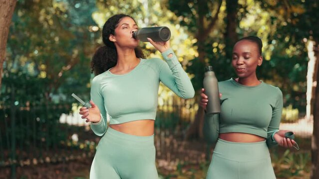 Fitness, drinking water and friends with women in park for running, training and bonding. Relax, happy and break with female runner and toast with bottle in nature for workout, exercise and wellness