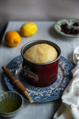 Step by step process of making sweet Ukrainian Easter bread paska. Paska rising in a special springform pan on vintage blue plate on table.