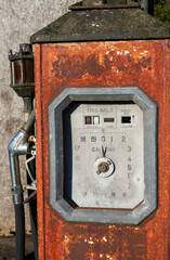 Fototapeta na wymiar A rusty and disused petrol pump by the side of a minor road with shilling indicators