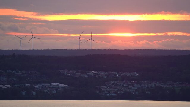 Wind Turbines in motion rotating generating green electricity at sundown with Clouds on a hill in Jonkoping Sweden. 