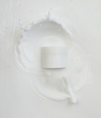 Cosmetic container white lotion droplet fly splashing. Milk lotion pour float to cosmetic bottle. Moisturizer lotion explosion spill. White background isolated high speed shutter freeze top view