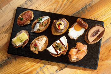 top view of slate table of spanish tapas or pintxos - obrazy, fototapety, plakaty