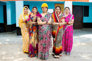 Fototapeta na wymiar Group of confident young indian women wear sari standing with female engineer, women empowerment. Industrial factory workers. Skill india. job career opportunities, Aspiration, achievement, sisterhood