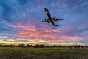 Low angle shot of airplane flying over field during scenic sunset