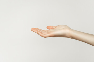 female hand holding or showing something on gray background