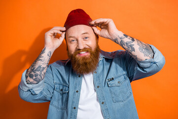 Closeup photo of red hair beard man wear denim jacket with tattoos fixing his beanie hat new trend...