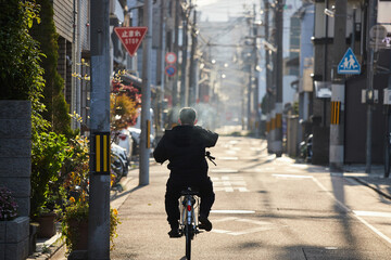 京都の町並みで自転車を乗っている男性の後ろ姿