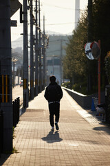 京都の夕方の町並みで歩く一人の若者の後ろ姿