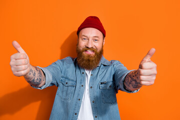Portrait of cheerful nice person toothy smile hands fingers demonstrate thumb up isolated on orange color background