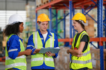 Multiethnic industrial workers checking their logistic lists while working with transportation of goods in warehouse