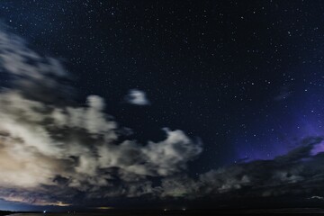 Fototapeta na wymiar Starry glowing in the night sky, clouds around