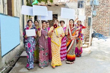 Group of traditional indian woman holding blank cardboard placard protesting yelling in megaphone....