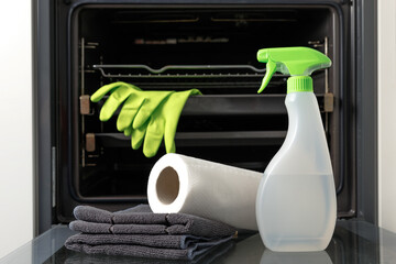 Oven cleaner kit on open door. Bottle with ecological health-friendly detergent, wipes and gloves...