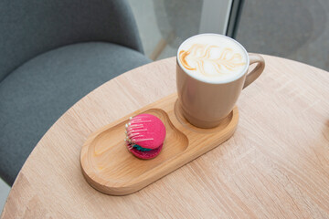 cup of coffee latte and colorful pink macaroons on wooden table