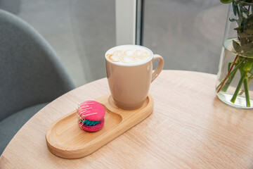 cup of coffee latte and colorful pink macaroons on wooden table