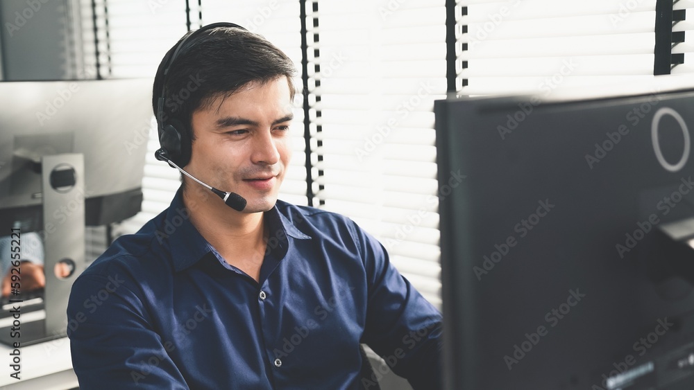 Aufkleber young competent asian male call center agent working at his computer while simultaneously speaking w