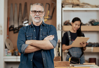 Portrait of male carpentry standing with Asian wife in handmade furniture business. multicultural family working together at wood carpenter shop as owner. Diversity ethnic couple in artisan woodwork.