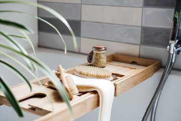 Wooden tray with home spa supplies and bathrobe in modern home bathroom for relaxing rituals. Spa...