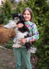 A girl of 8 years old plays and runs with her dog in the yard on the lawn. Little Girl with a Shih Tzu dog