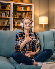 Obraz premium Mature senior woman practice guided meditation manifestation at home
