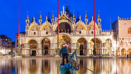 San Marco square with Campanile and San Marco's Basilica - Venice flooded from the high water and Venetian gondolier punting gondola  - obrazy, fototapety, plakaty