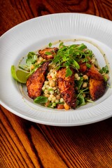 Vertical closeup of chicken salad in a white plate on the wooden table