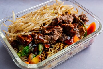 Closeup of Lo mein dish with a sauce and vegetables on a glass platev