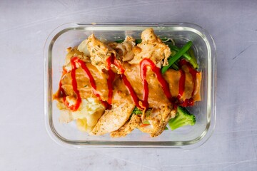 Closeup of chicken with a sauce and vegetables on a glass plate