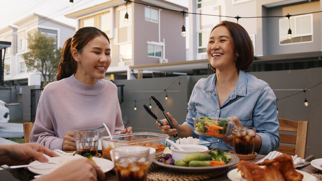 Mom Enjoy Thai Meal Cooking For Family Day Home Dining At Dine Table Cozy Patio. Mum Passing Serving Food To Group Four Asia People Young Adult Man Woman Friend Fun Joy Relax Warm Night Picnic Eating.