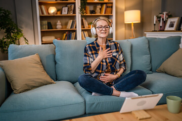 Obraz premium Mature senior woman practice guided meditation manifestation at home