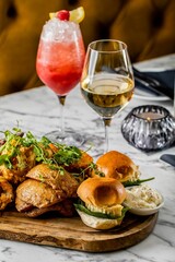 Vertical shot of healthy small burgers and snacks with glass of drinks in the background