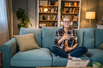 Obraz premium Mature senior woman practice guided meditation manifestation at home