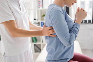 Fototapeta premium cropped view of physiotherapist examining injured back of woman in consulting room.