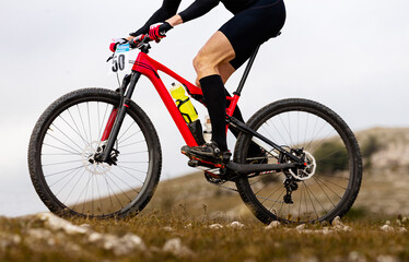Fototapeta na wymiar close-up male cyclist in compression socks riding on red mountain bike in cross-country cycling race