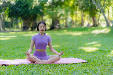 Young Asian woman doing yoga in the garden for exercise and good health. In the park Asian fitness woman doing yoga and relaxing with sportswear in green park in summer