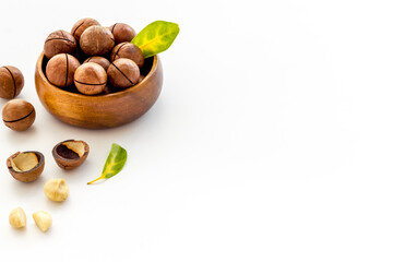 Shelled macadamia nuts in bowl with green leaves. Protein food