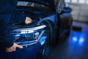 Mechanic changing car headlight in a workshop
