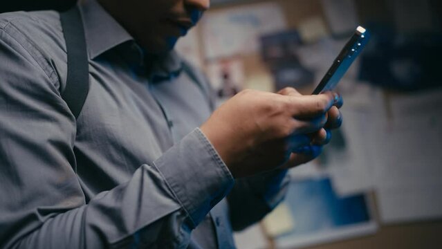 Police detective communicating with colleague on smartphone, investigation