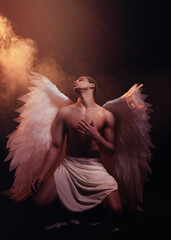 Young strong angel with white wings from heaven. Angel with muscular body. Sensual man
