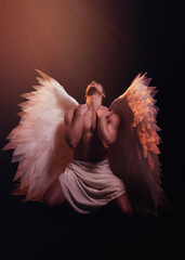 Young strong angel with white wings from heaven. Angel with muscular body. Sensual man