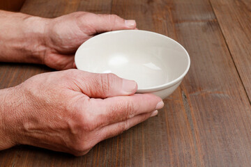 Hungry man waiting for his meal over empty plate on wooden table.