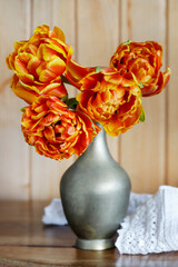 Bouquet of orange tulips in golden vase.