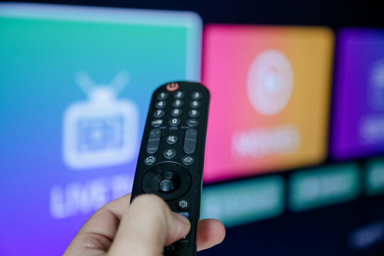 Controle de tv acionando para ligar e assistir series e filmes na televis&atilde;o smart com fundo borrado.	