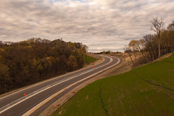 Obraz premium Road Winds Up Hill With Newly Sown Grass
