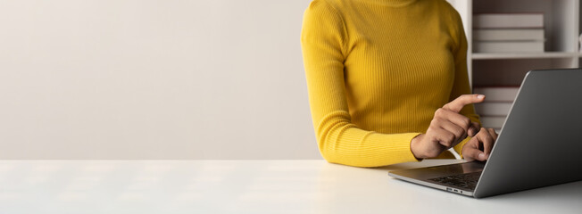 Close up view of young woman working and typing on laptop computer at her desk.