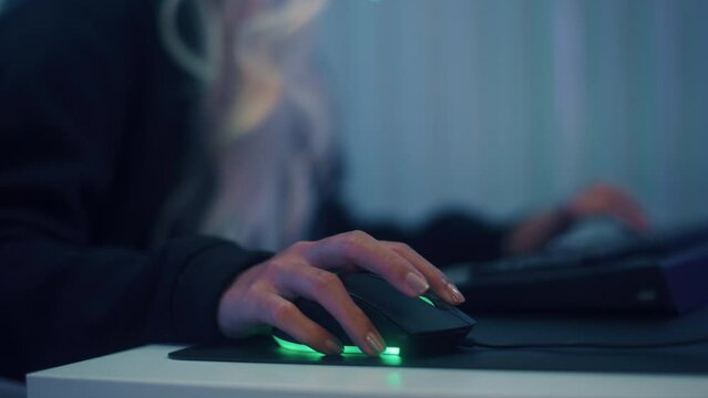 Close up of Woman Gamer Hands using computer mouse and typing, pushing keyboard button playing game. Asian Gamer Girl playing video game at night in Neon Led Light room.