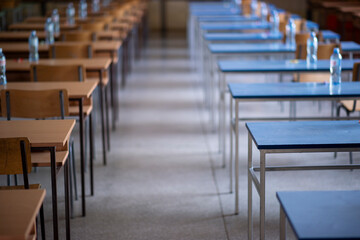 Exam examination room or hall set up ready for students to sit test. multiple desks tables and chairs. Education, school, student life concept.