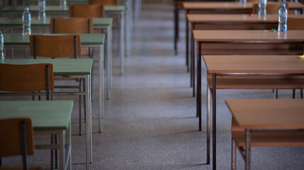 Exam examination room or hall set up ready for students to sit test. multiple desks tables and chairs. Education, school, student life concept.