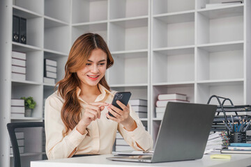Young asian businesswoman beautiful charming smiling and using the mobile phone in the office.