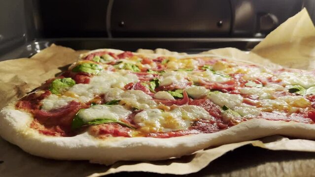 Delicious Homemade Pizza baking inside the oven for a social gathering of family and friends. Pizza on Baking Paper in a gas oven.